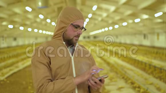使用智能手机对家禽养殖场进行统一检查的农民视频的预览图