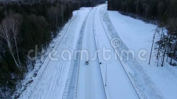 鸟瞰一辆孤独的汽车沿着一条森林雪道驶向黎明家庭汽车旅行视频的预览图