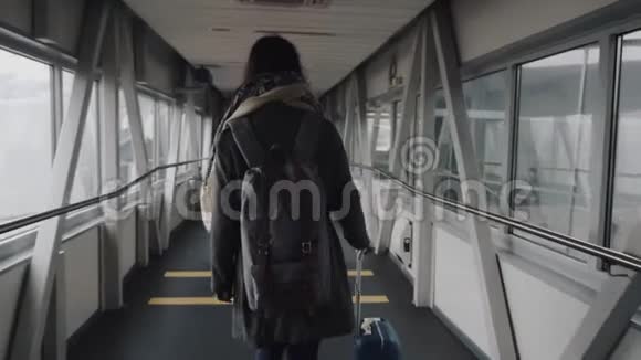 镜头跟随年轻快乐的旅游妇女沿着现代机场出发大厅走廊慢动作视频的预览图
