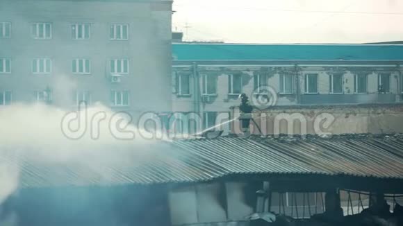 消防队员或梯子上的消防员在公寓屋顶上用烟雾扑灭燃烧的火焰视频的预览图