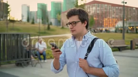 中档成年男子在大城市公园用智能手机走路视频的预览图