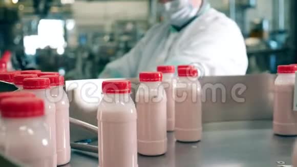 奶厂工人从传送带上拿着酸奶的瓶子视频的预览图