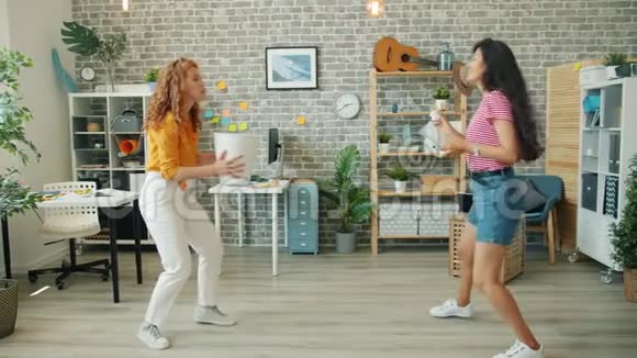 年轻的女士在办公室的篮子里扔纸球享受着有趣的游戏视频的预览图