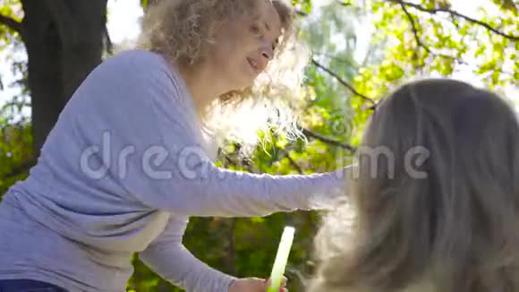 年轻的白种人母亲给她可爱的小女儿肥皂泡的肖像家里有两个孩子玩得开心视频的预览图