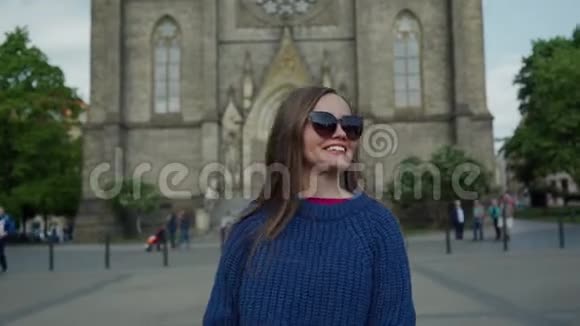 美丽的阳光明媚的一天戴着太阳镜的甜美长发女孩离开了宏伟的圣路德米拉教堂视频的预览图