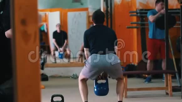 体育训练在健身房锻炼的男人一个穿着蓝色短裤的男人蹲在前台体重增加视频的预览图