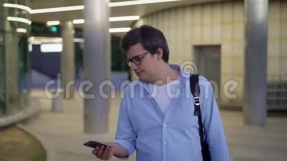 中锋戴着眼镜和蓝色衬衫的男子拿出电话打电话视频的预览图