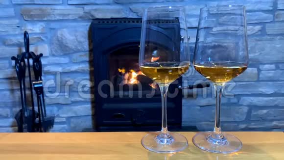 在燃烧的壁炉前男女双手捧着两杯葡萄酒这是一个浪漫的夜晚视频的预览图
