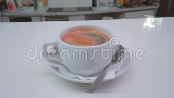 一杯咖啡放在碟子上上面有一张餐巾纸和一茶匙视频的预览图