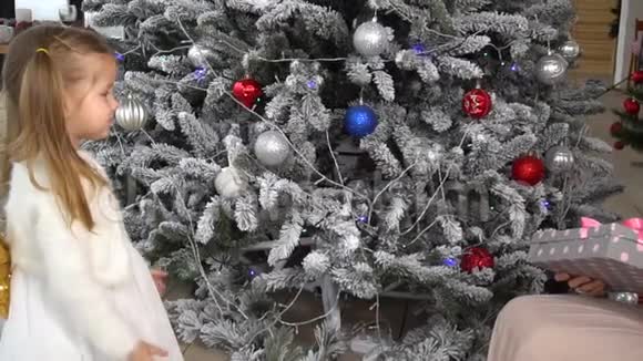 妈妈送给她的小女孩一个带有圣诞树的礼物盒视频的预览图