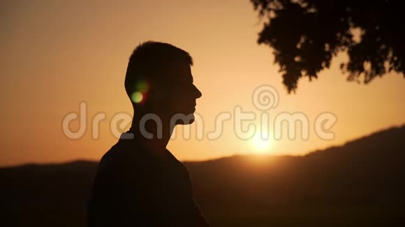 一个男人在美丽的日落中触摸和检查智能手表的Sillhouette背景视频的预览图
