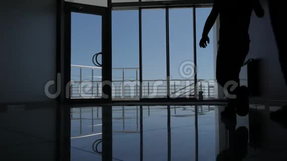 一个女人带着一个小女儿穿过酒店的玻璃门到长廊美丽的海景视频的预览图