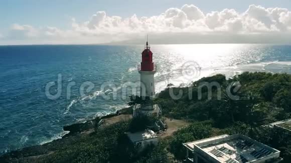 海岸上有棕榈树和白色灯塔大西洋上灯塔的鸟瞰图视频的预览图