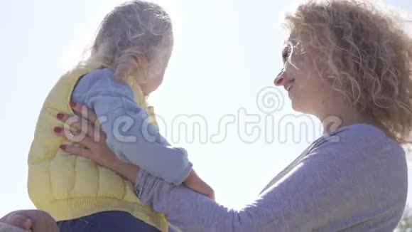 侧面看金发白种人女人卷发抱着小漂亮女孩开心的微笑母女视频的预览图