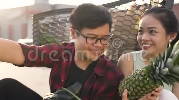 微笑着的越南男人和女人坐在市场手推车前拿着食物用苹果自拍视频的预览图