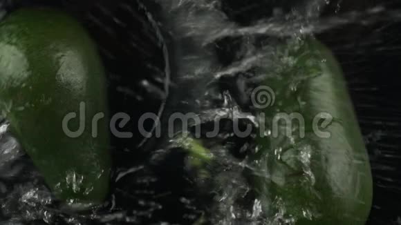 慢动作两个半鳄梨落在水里的黑色背景俯视图视频的预览图