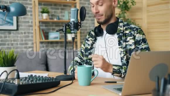 快乐的男人享受咖啡在现代工作室录制播客音频视频的预览图