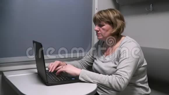 一个女人在一辆移动的火车上拿着一台笔记本电脑在窗边工作视频的预览图