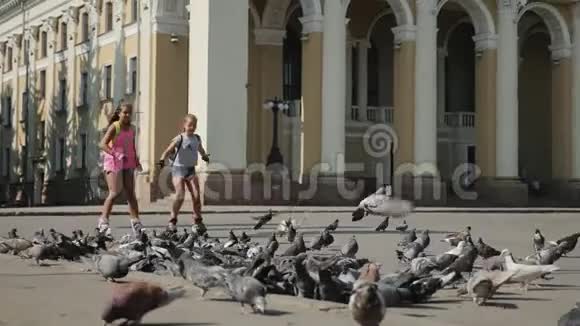 两个十几岁的女孩在城里溜冰一群鸟飞了起来视频的预览图
