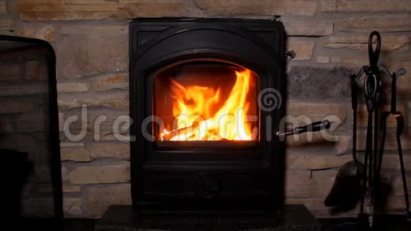 美丽的橙色火焰从燃烧的柴火在铁黑壁炉特写一个舒适的房子的概念视频的预览图