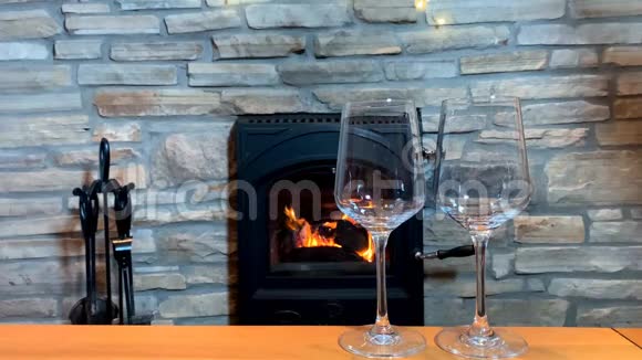 壁炉前的桌子上摆着两杯葡萄酒这是一个浪漫的夜晚的概念视频的预览图