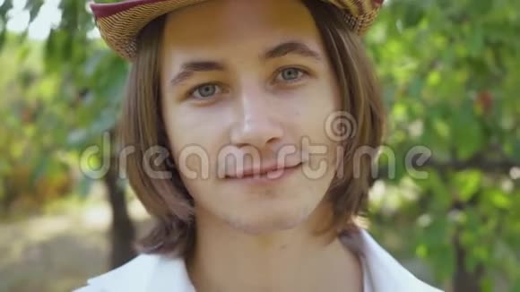 一个年轻人在公园或花园里看相机的特写肖像英俊的白种人男孩微笑休闲视频的预览图