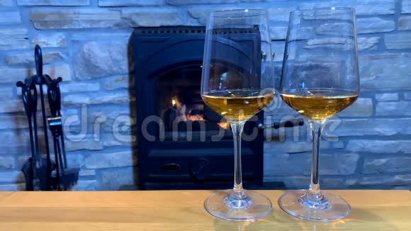 壁炉前的桌子上摆着两杯葡萄酒这是一个浪漫的夜晚的概念视频的预览图