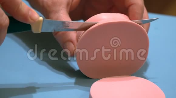 一个女人把粉红色的美味的煮熟的香肠切成碎片视频的预览图