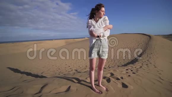 一个美丽的女性模特在沙漠之旅站在沙丘岭日落和姿势炎热干燥沙漠时尚女士视频的预览图