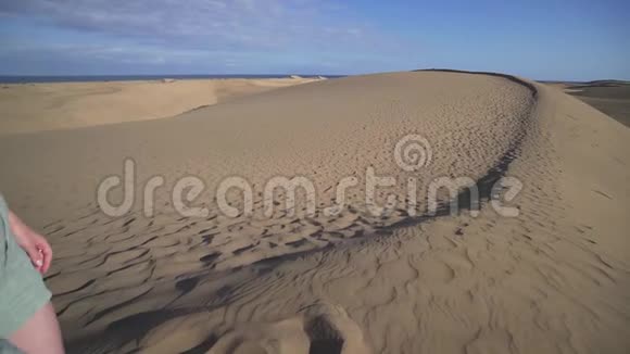 一个穿着休闲服的快乐女人沿着大西洋海岸沙漠中的一个高高的沙丘奔跑生活方式视频的预览图