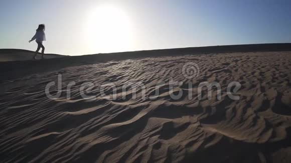 日落时分沙漠中一个美丽的女孩沿着沙丘散步的剪影西班牙大加那利马斯帕洛马斯沙漠视频的预览图
