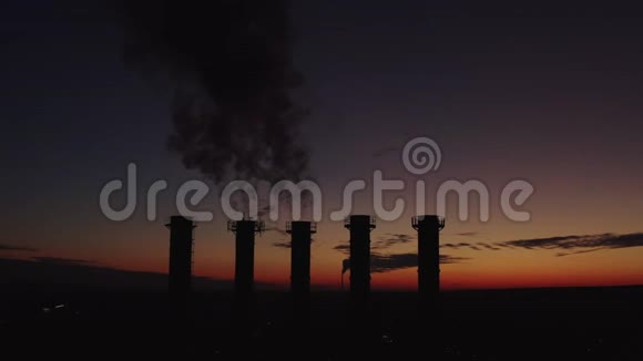 美丽的日落笼罩着一座冒烟的热电厂太阳穿过冷却塔和烟囱浓烟升起视频的预览图