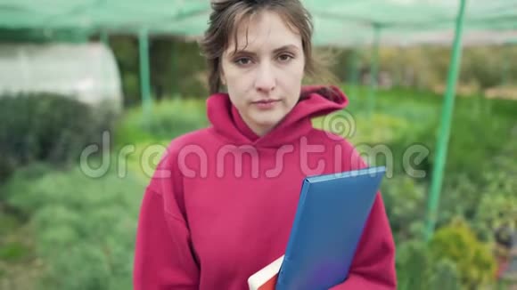 一位年轻的女企业家在一个种植农场的肖像美丽的花匠女孩看着相机植物在视频的预览图