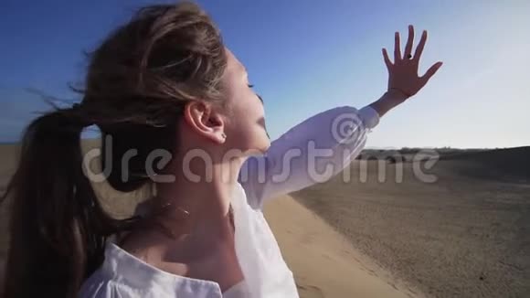 女孩透过手掌的手指看着干燥沙漠中的太阳站在沙滩上她的手在视频的预览图