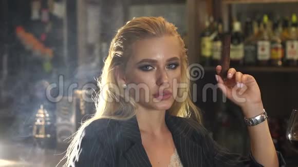 一个年轻的女人晚上坐在酒吧里抽雪茄她是一个人视频的预览图