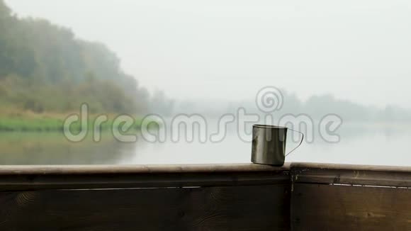 一杯热咖啡放在一个旧的木栏杆上复古色调与复制空间河面雾的景色视频的预览图