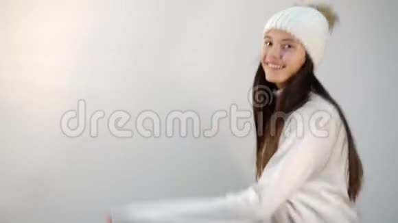 穿着毛衣和帽子的布鲁内特女孩在轻墙上跳舞视频的预览图