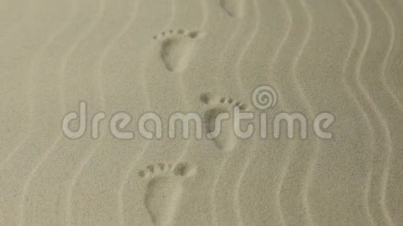 放大有花纹的脚印的人痕迹延伸到远处沙中的脚印视频的预览图
