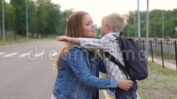 快乐的妈妈在放学前拥抱她的小儿子他们站在路上拥抱视频的预览图