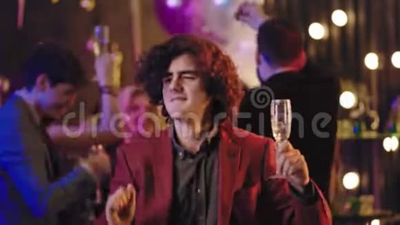 在派对上跳舞的有魅力的男人他拿着一杯香槟享受着夜晚的乐趣移动着有趣的感觉视频的预览图