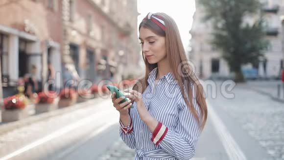 年轻可爱的迷人女人棕色头发佩戴头巾和条纹服装使用她的智能手机的肖像女孩视频的预览图