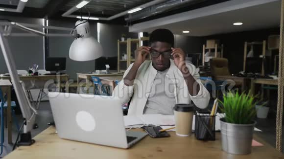 疲惫的非洲男人在现代办公室等着下班视频的预览图