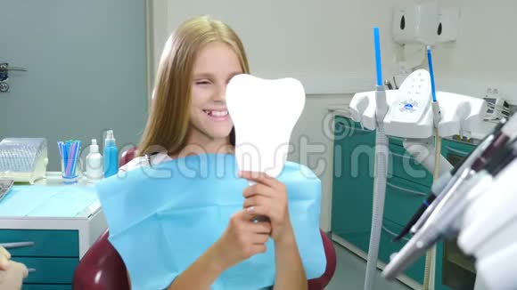 牙牙健康理念微笑的女孩坐在牙科椅上看镜子的肖像医疗治疗视频的预览图