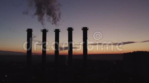 在一个大城市和日落的背景下五个冷却塔的剪影在吸烟的时候美丽的日落视频的预览图