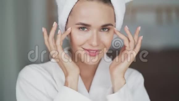 穿着浴袍头上有毛巾的女人肖像脸上涂着奶油视频的预览图