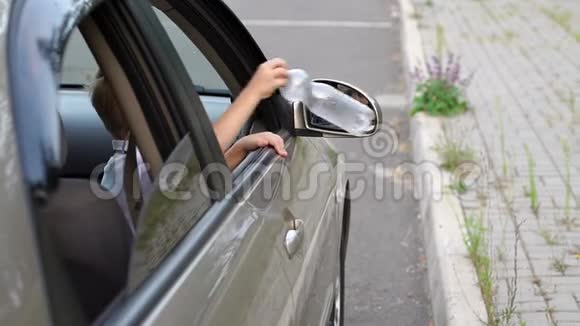小男孩在路上把塑料瓶从车窗扔了出去慢动作视频的预览图