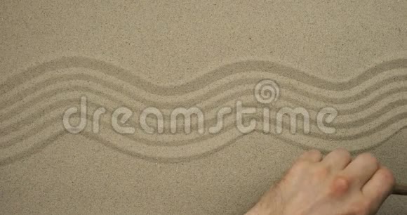 雄手在沙中画波浪线上景视频的预览图