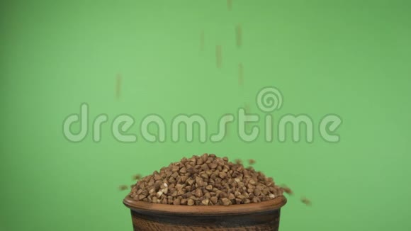 荞麦颗粒掉进拥挤的粘土碗里从里面掉出来孤立在绿色屏幕上视频的预览图