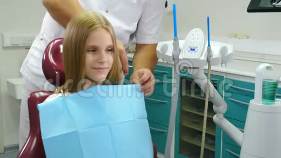 戴牙椅的漂亮小女孩儿童牙科为小病人准备治疗的牙医男性牙医视频的预览图