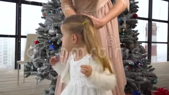 妈妈给小女孩留了个发型小女孩身后有圣诞树视频的预览图